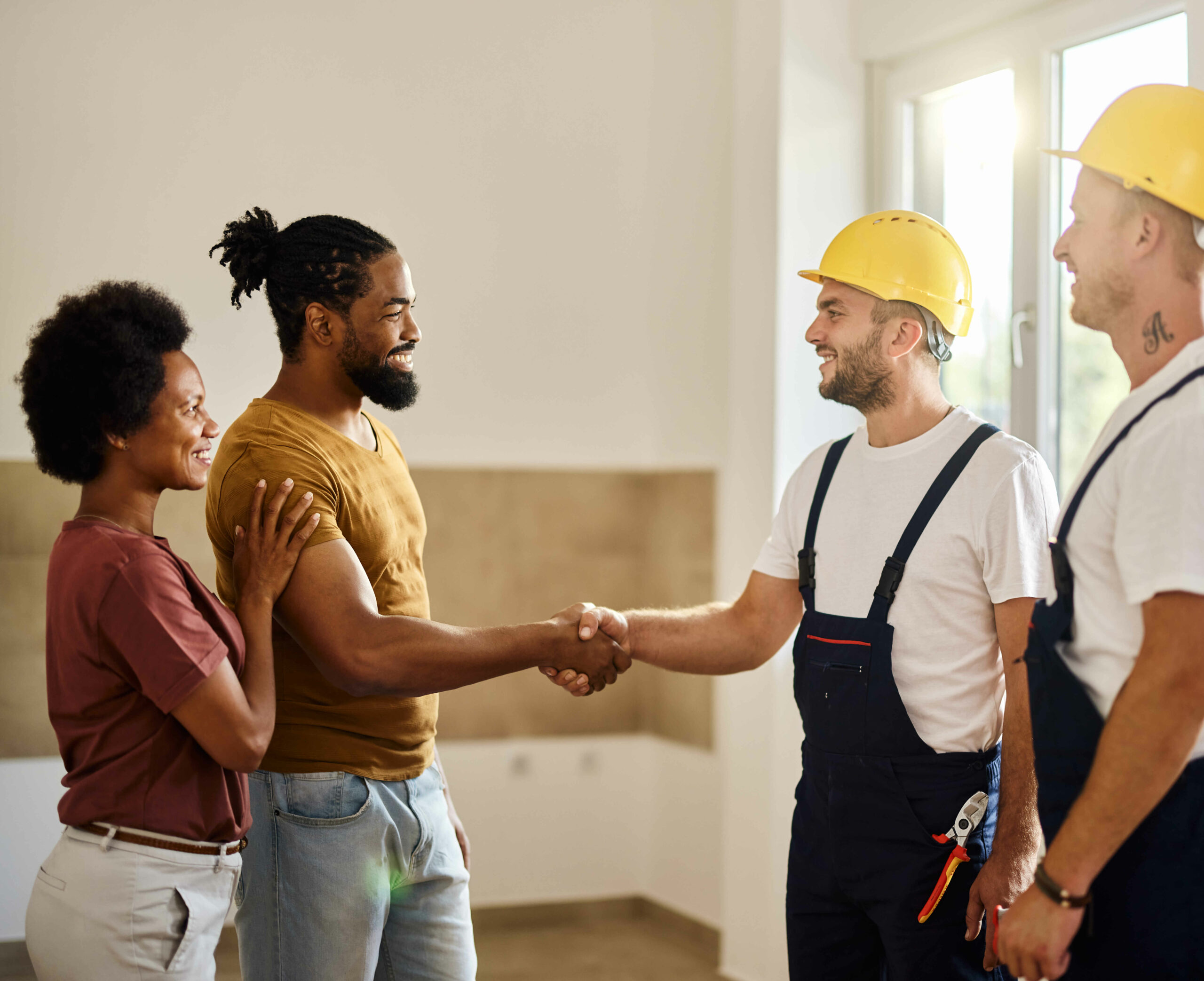 Happy black couple came to an agreement with manual workers at renovating apartment.